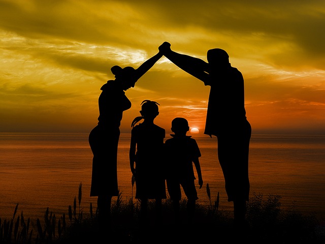 Mom, dad and two children together at sunset.