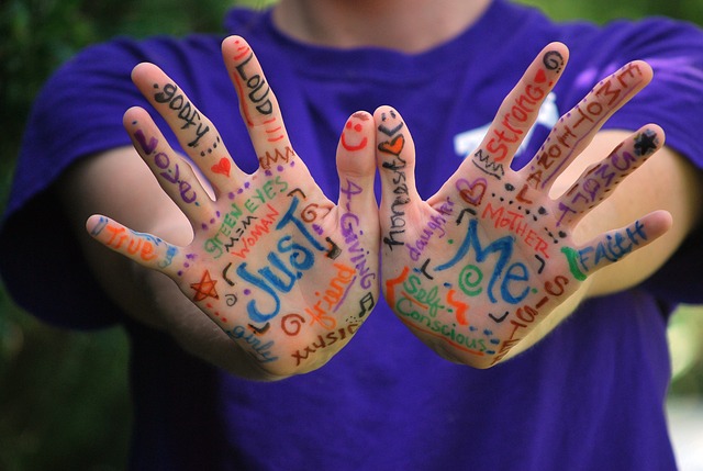 Two palms of youngster painted with colorful hand-written notes.