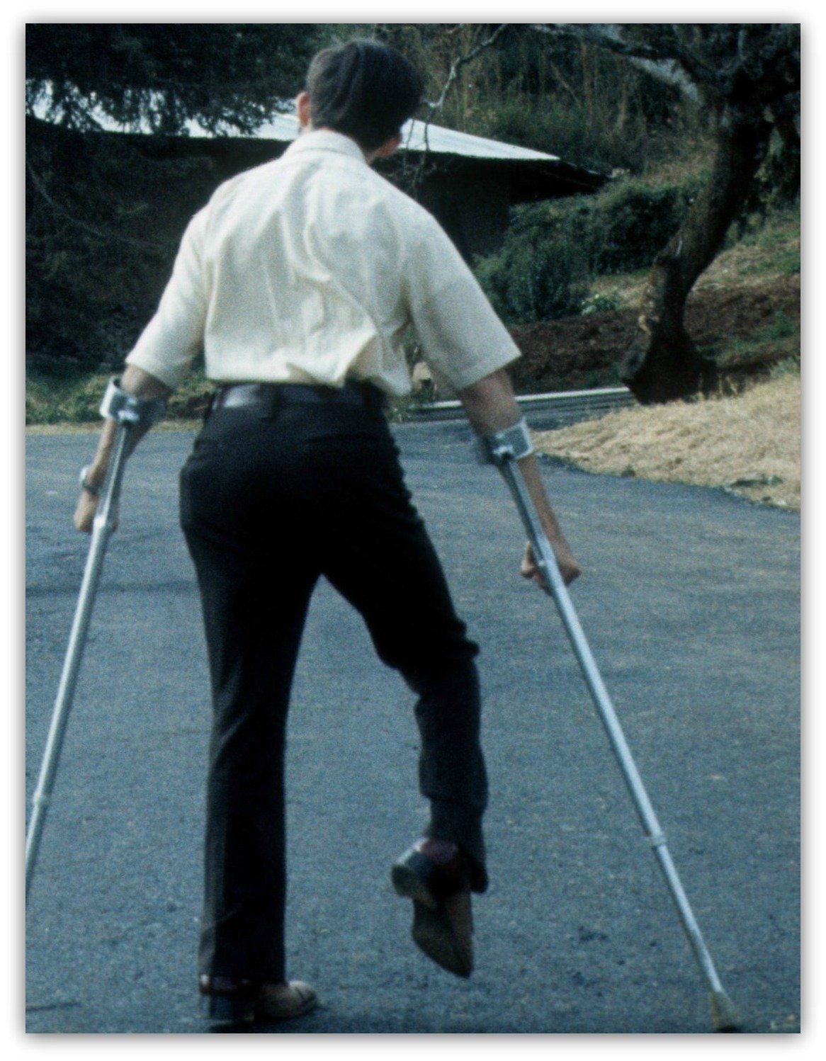 Jim Hasse (from backside) walking up hill with Canadian crutches.