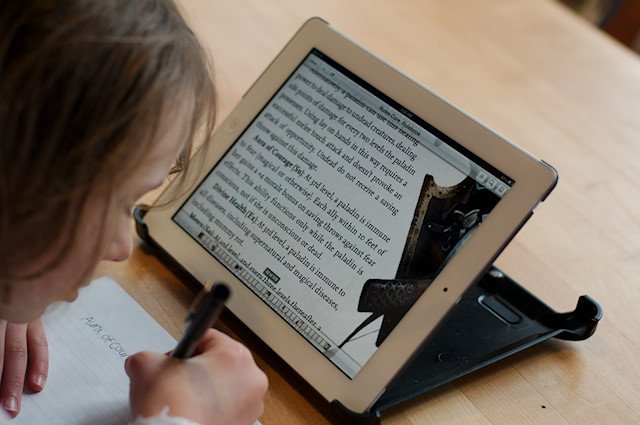 Motivated Kids: Elementary girl taking notes from iPad.